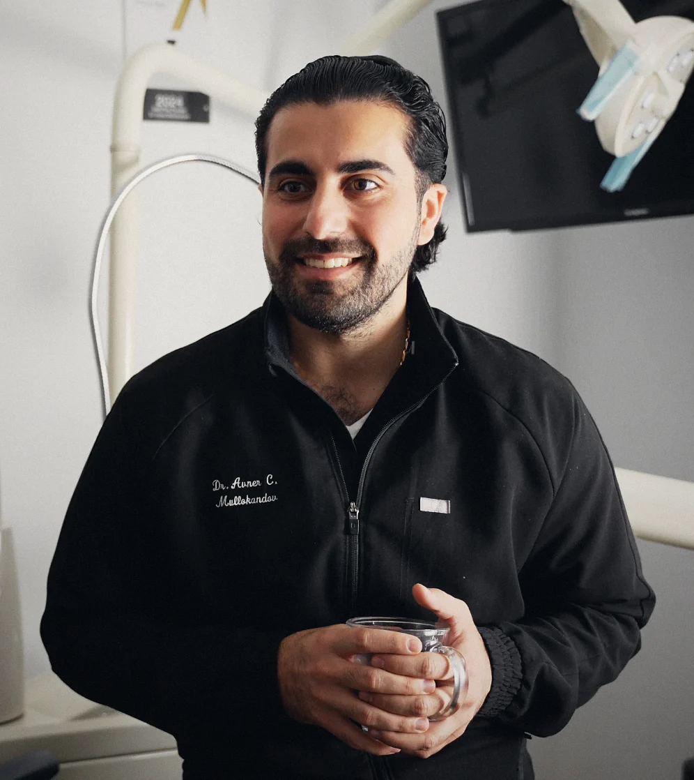 Dr. Avner C. Mullokandov in a treatment room at Dentist on Madison, holding a glass mug